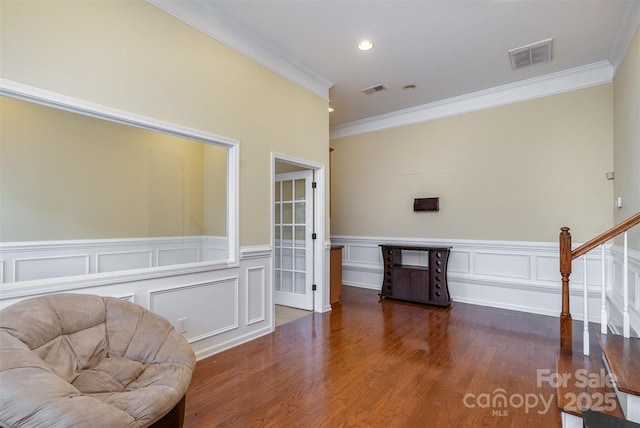 sitting room featuring dark wood-type flooring, visible vents, ornamental molding, and stairs