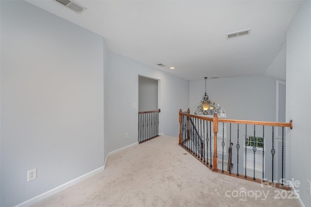 hall with carpet, visible vents, vaulted ceiling, and baseboards