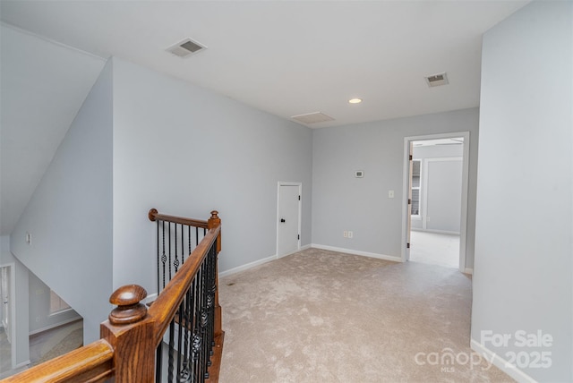 corridor featuring baseboards, visible vents, light colored carpet, and an upstairs landing