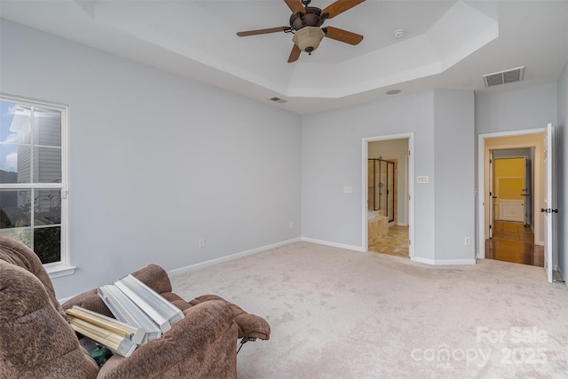 living area with baseboards, visible vents, light colored carpet, ceiling fan, and a tray ceiling