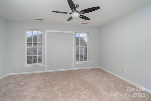 spare room with light carpet, a healthy amount of sunlight, and visible vents