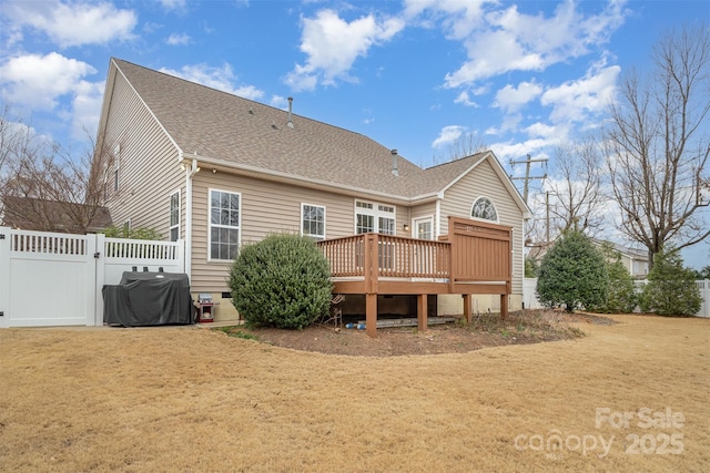 back of house featuring a yard, roof with shingles, a wooden deck, and fence