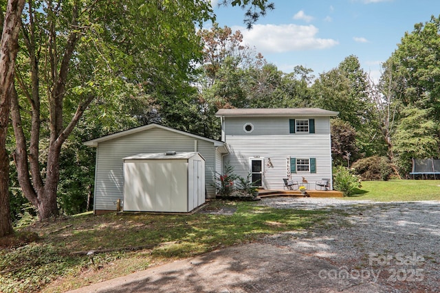 rear view of house featuring a lawn, a wooden deck, a shed, and a trampoline