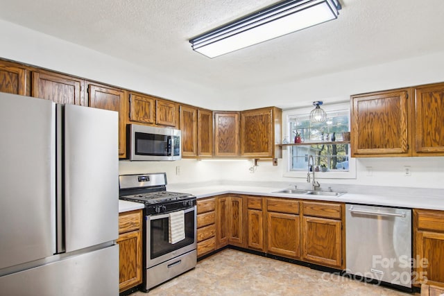 kitchen featuring a textured ceiling, stainless steel appliances, and sink