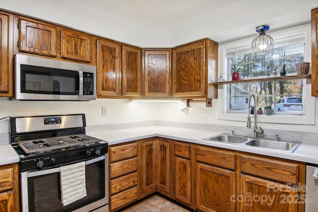 kitchen with pendant lighting, sink, stainless steel appliances, and an inviting chandelier