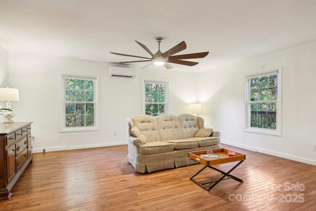 living room featuring a wall mounted air conditioner, light hardwood / wood-style floors, ceiling fan, and a healthy amount of sunlight