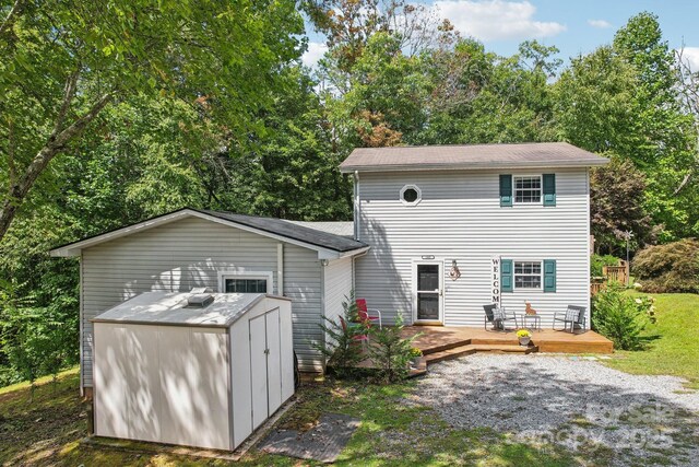 back of property featuring a storage shed and a deck