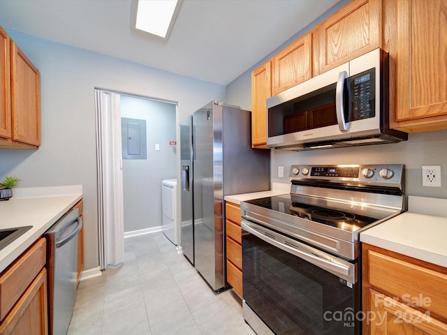 kitchen featuring light tile patterned floors, stainless steel appliances, washer / clothes dryer, and electric panel