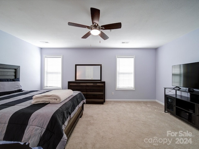 bedroom with ceiling fan, multiple windows, and light colored carpet