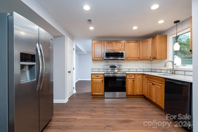 kitchen featuring hanging light fixtures, sink, backsplash, dark wood-type flooring, and stainless steel appliances