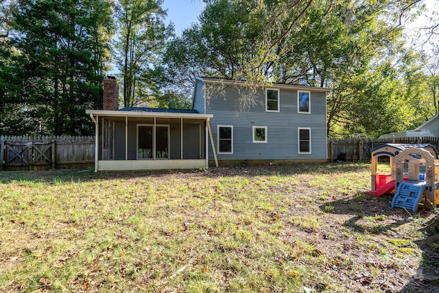 rear view of house with a sunroom and a lawn