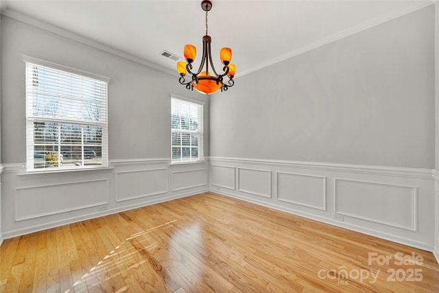 unfurnished room with hardwood / wood-style flooring, ornamental molding, and an inviting chandelier