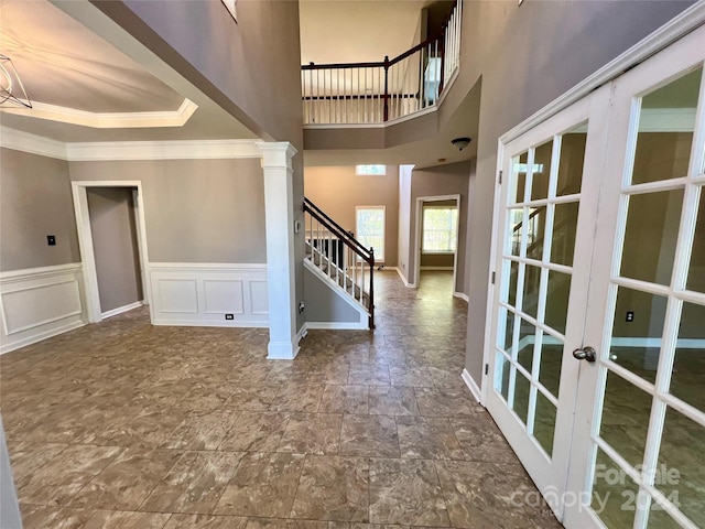 entrance foyer featuring french doors, crown molding, a high ceiling, and decorative columns