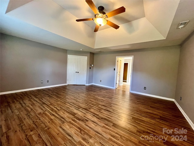 interior space with hardwood / wood-style flooring, a raised ceiling, and ceiling fan