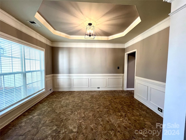 spare room featuring crown molding, a raised ceiling, and a chandelier