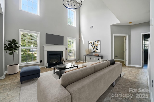 3007 Gambrill Falls Dr, Indian Trail, NC 28079 - living area featuring a towering ceiling, healthy amount of natural light, baseboards, a fireplace with flush hearth, and a chandelier