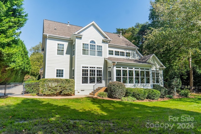 back of property with a lawn and a sunroom