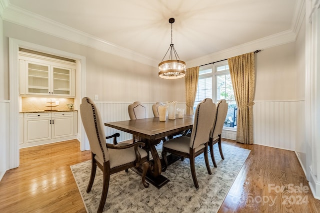 dining space featuring light hardwood / wood-style floors, a notable chandelier, and ornamental molding