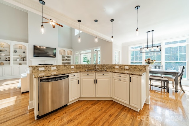 kitchen with a center island with sink, stainless steel dishwasher, light wood-type flooring, ceiling fan with notable chandelier, and decorative light fixtures