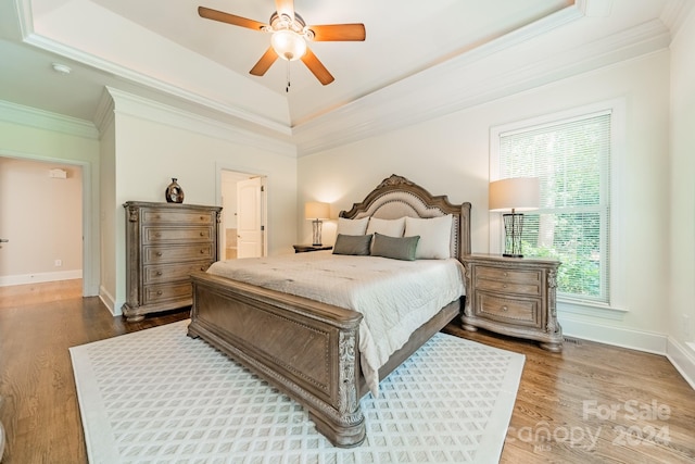 bedroom featuring ceiling fan, hardwood / wood-style flooring, multiple windows, and a raised ceiling