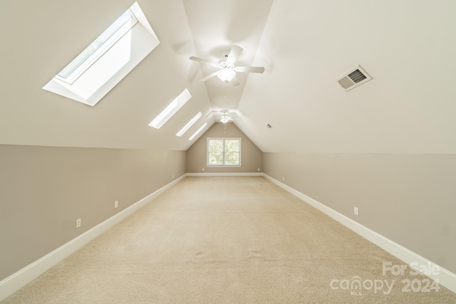 bonus room with lofted ceiling with skylight and light colored carpet