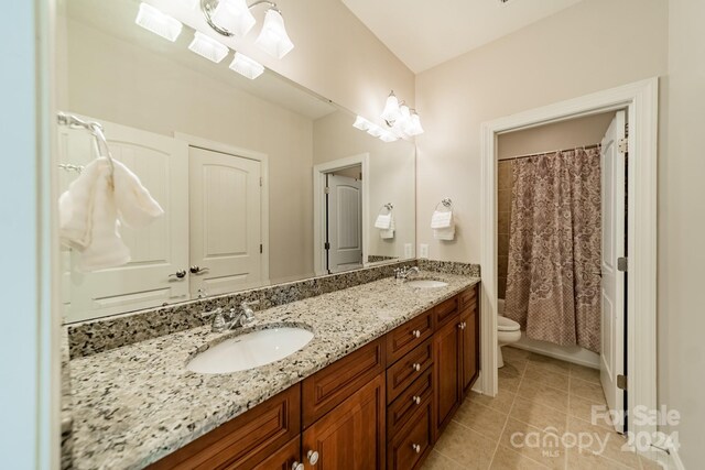 bathroom with a skylight, toilet, walk in shower, vanity, and tile patterned flooring