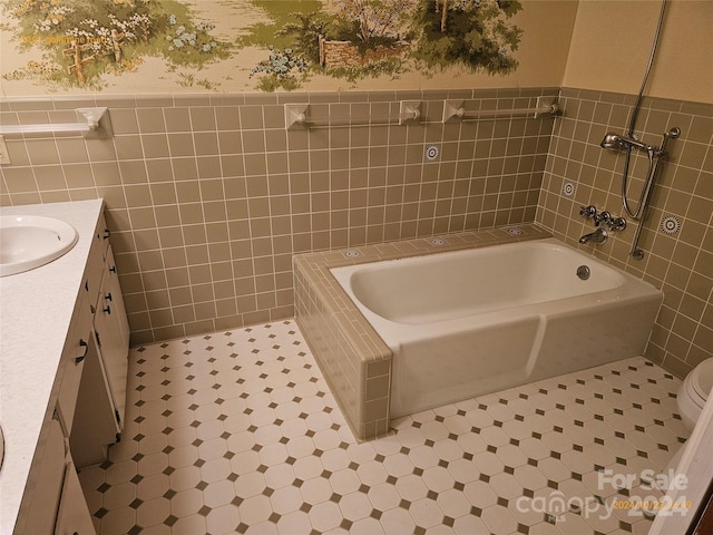 bathroom with vanity, toilet, tile walls, and a washtub