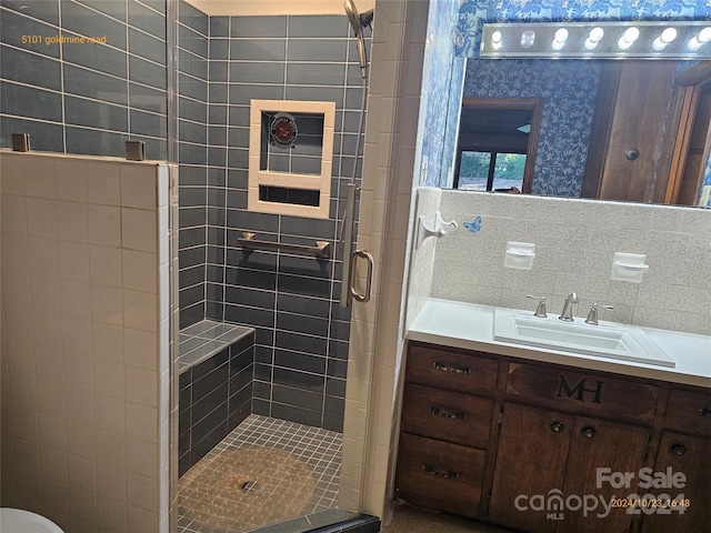 bathroom with vanity, decorative backsplash, tile walls, and a shower with door