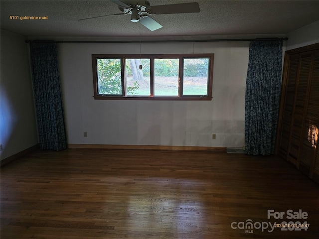 empty room with dark wood-type flooring, a textured ceiling, and ceiling fan