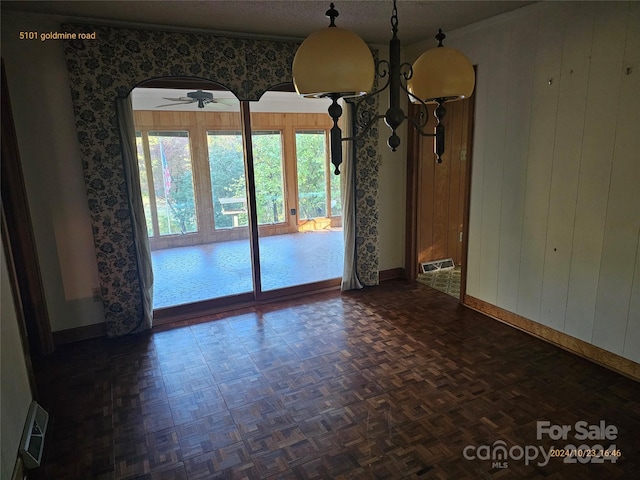 unfurnished dining area featuring dark parquet floors, wooden walls, and ceiling fan