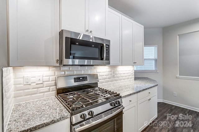 kitchen featuring white cabinets, light stone counters, backsplash, and appliances with stainless steel finishes