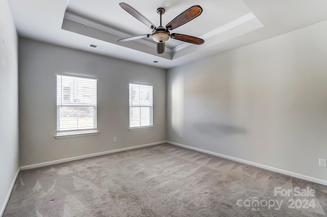 carpeted spare room with a tray ceiling, ceiling fan, and crown molding