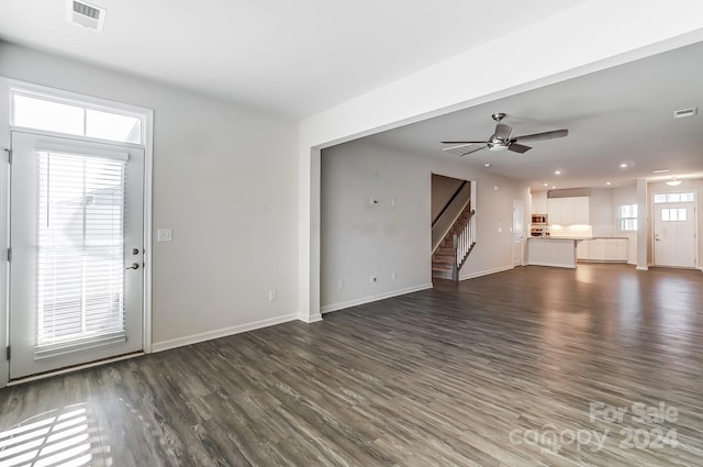 unfurnished living room with ceiling fan, dark wood-type flooring, and a wealth of natural light