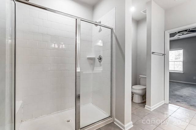 bathroom featuring tile patterned flooring, toilet, and a shower with shower door