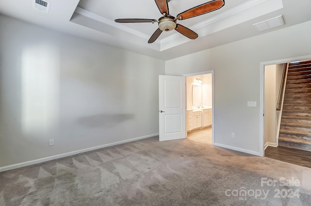 unfurnished bedroom with ceiling fan, a raised ceiling, light colored carpet, and crown molding