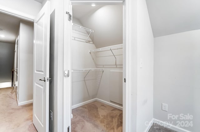 spacious closet featuring light colored carpet and lofted ceiling