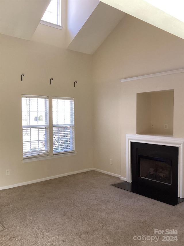 unfurnished living room featuring carpet floors and high vaulted ceiling