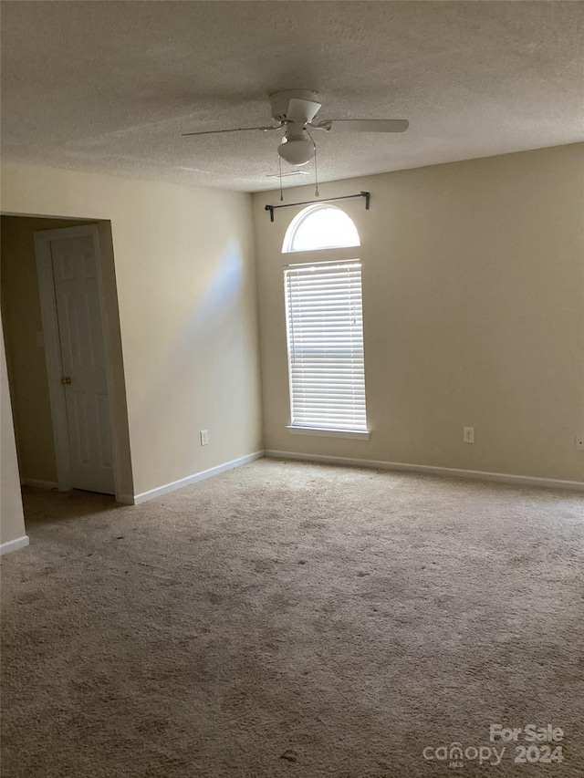 spare room featuring carpet, ceiling fan, and a textured ceiling