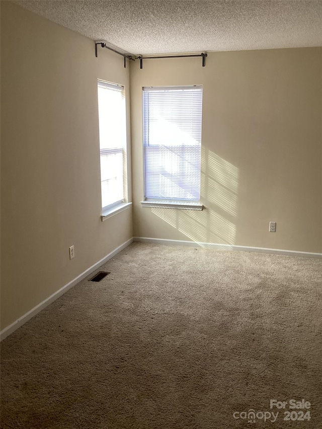 carpeted spare room with a textured ceiling