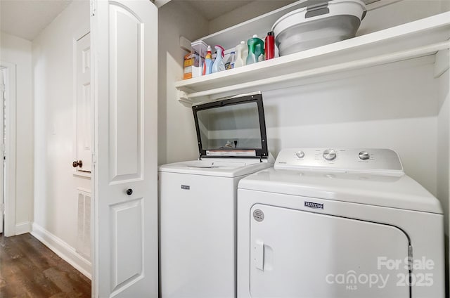 clothes washing area with washing machine and dryer and dark hardwood / wood-style floors