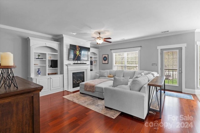 living room featuring built in shelves, crown molding, ceiling fan, and dark hardwood / wood-style floors