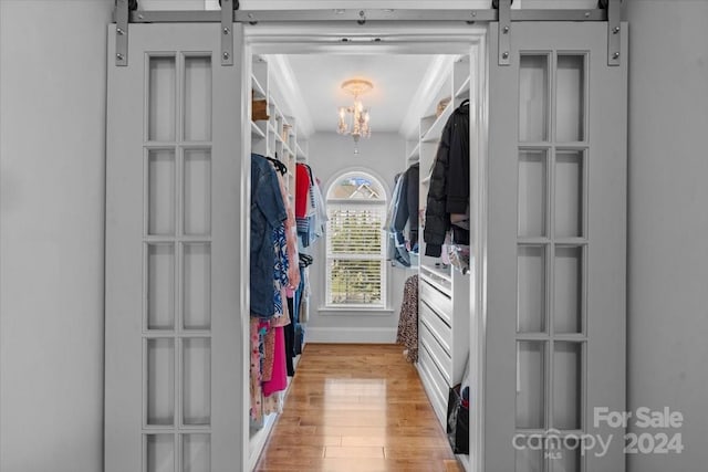 spacious closet featuring hardwood / wood-style floors and a notable chandelier