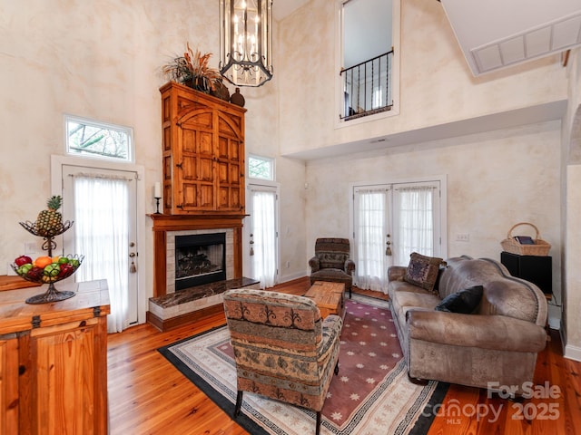 living area featuring light wood-style flooring, a tile fireplace, a wealth of natural light, and french doors