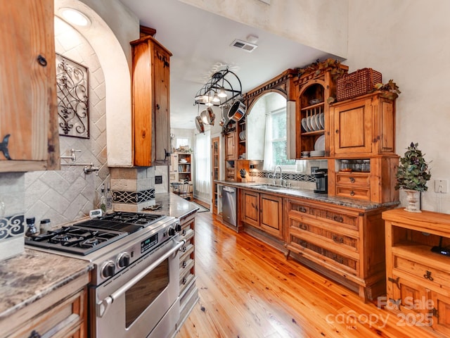 kitchen featuring brown cabinets, open shelves, visible vents, appliances with stainless steel finishes, and light wood-type flooring