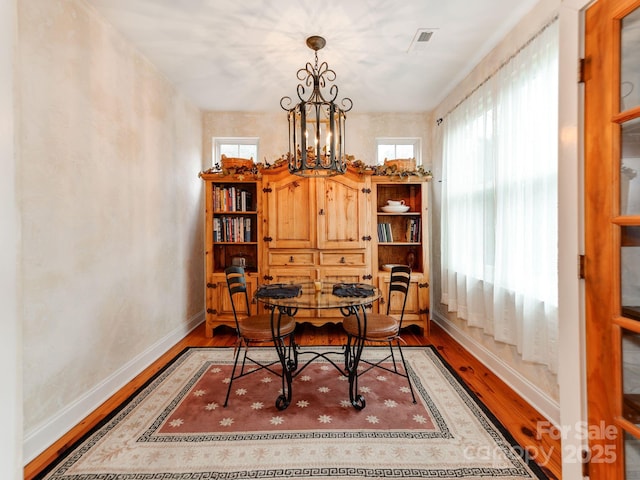 dining room featuring a notable chandelier, baseboards, and wood finished floors