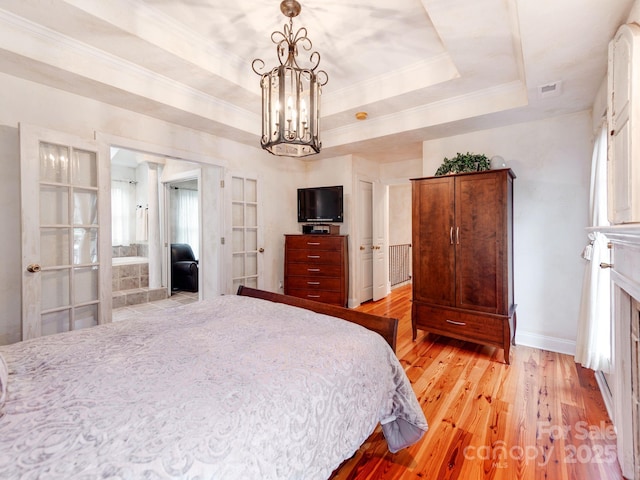 bedroom with light wood finished floors, a tray ceiling, multiple windows, and crown molding