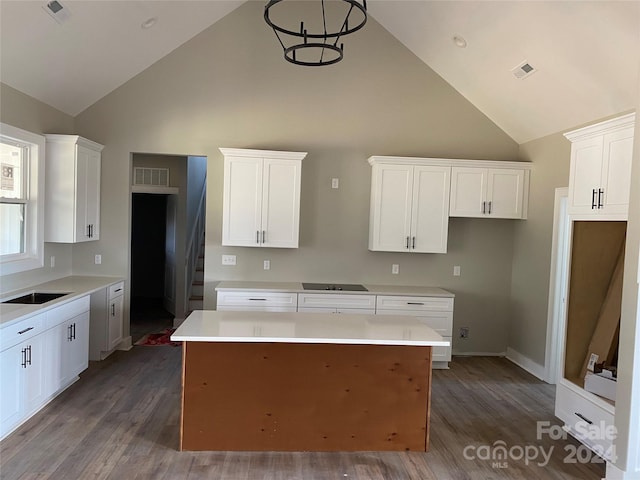 kitchen featuring high vaulted ceiling, white cabinetry, a kitchen island, and hardwood / wood-style flooring