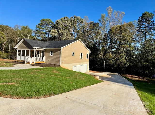 view of front of home with covered porch, driveway, a front lawn, and a garage