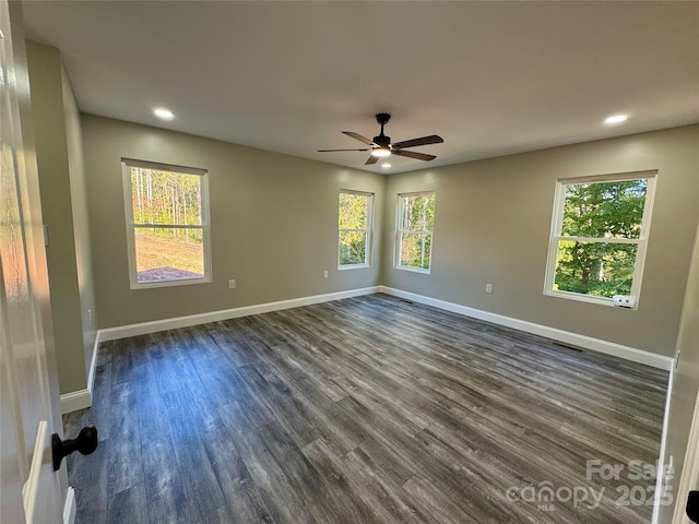 unfurnished room with recessed lighting, a healthy amount of sunlight, dark wood finished floors, and baseboards