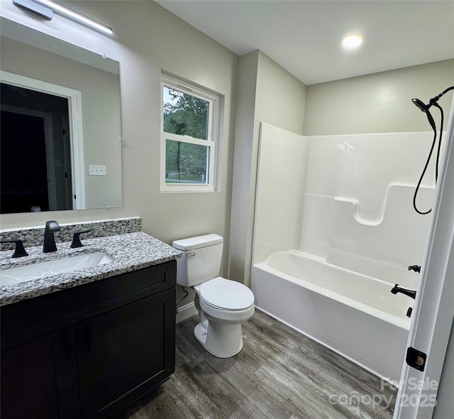 bathroom with washtub / shower combination, vanity, toilet, and wood finished floors